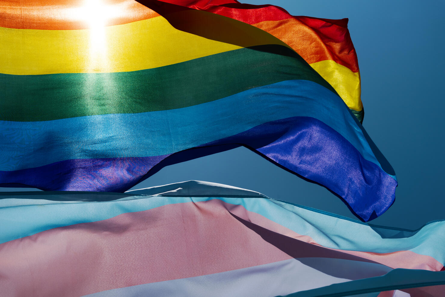 gay and transgender pride flags waving on the sky