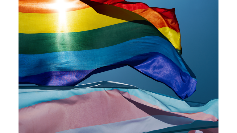 gay and transgender pride flags waving on the sky