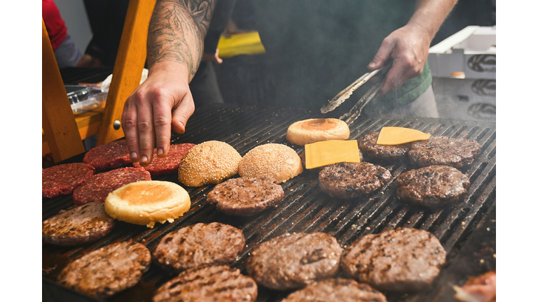 Midsection Of Man Preparing Burgers On Barbecue Grill