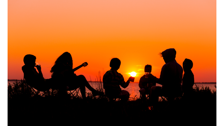 Silhouette of people sitting on the beach with campfire at sunse