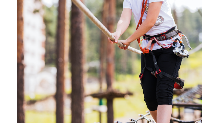 Close up of a child wearing safety equipment when holding onto a rope