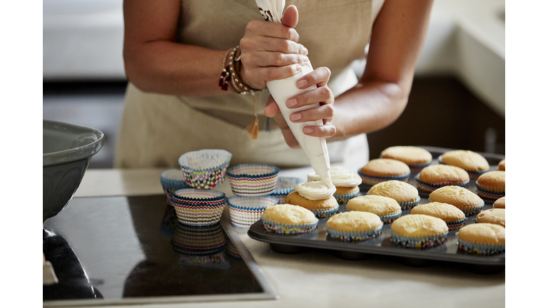 Woman icing cupcakes at kitchen counter