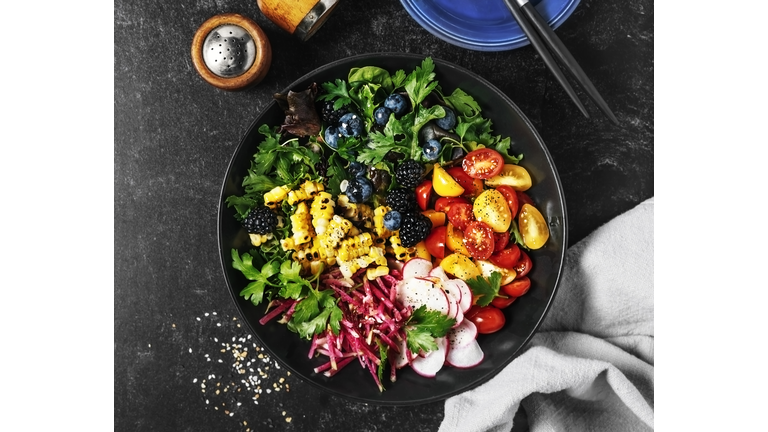 Bowl of fresh salad on black background