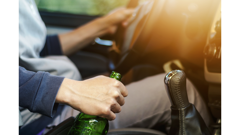 Drinking and driving ,man drinking alcohol and using mobile phone while driving car ,concept drive safely while using a cell phone or drunk alcohol