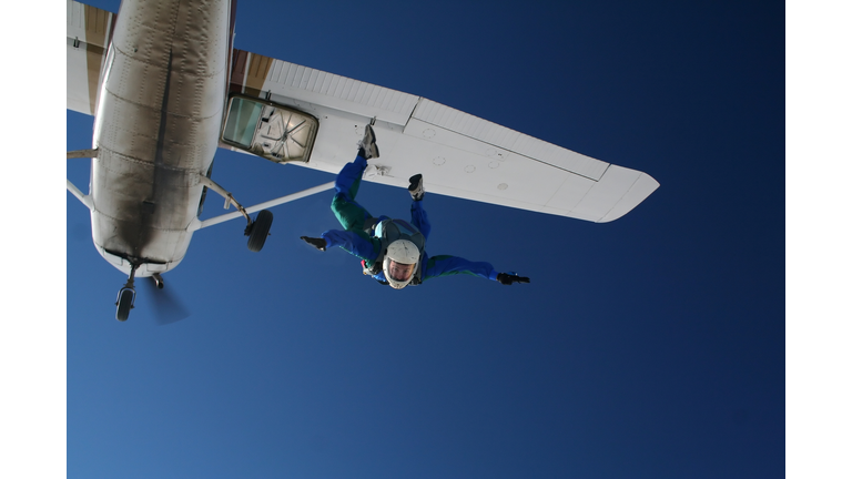 Skydiver exiting a small airplane