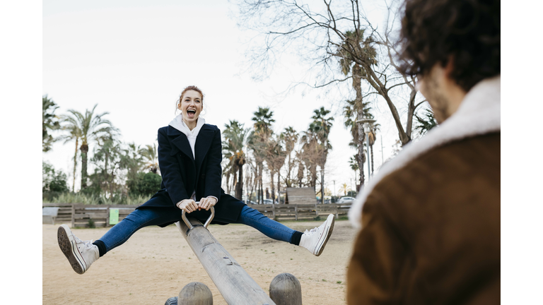 Exuberant couple on a seesaw at a playground