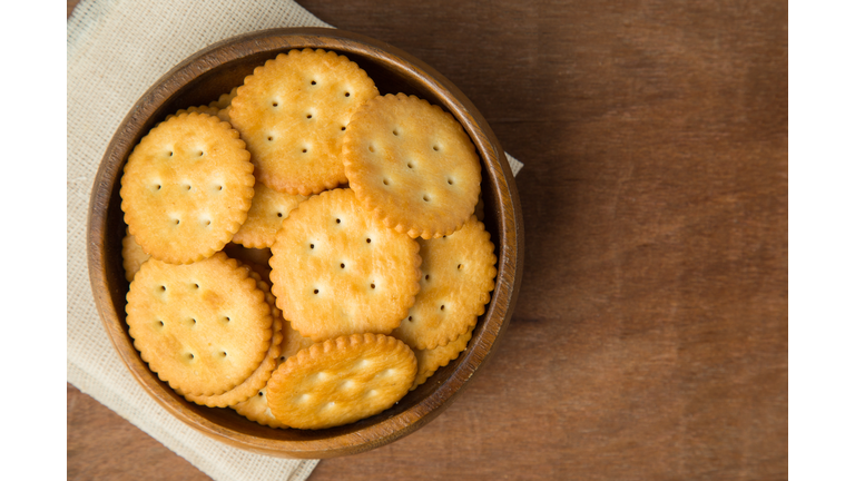 Round salted cracker cookies in wooden bowl putting on linen and wooden background
