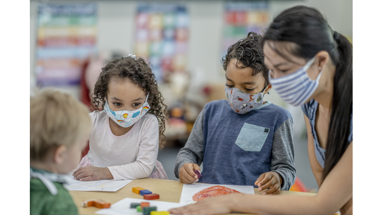 Group of children colouring while wearing masks