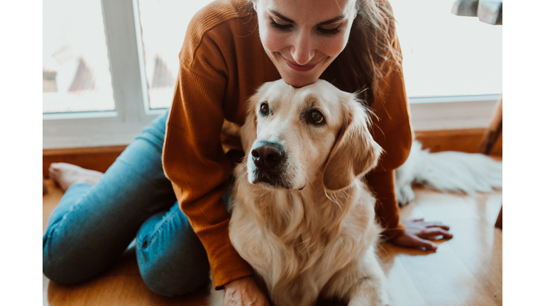 Smiling Woman With Dog Sitting On Floor At Home