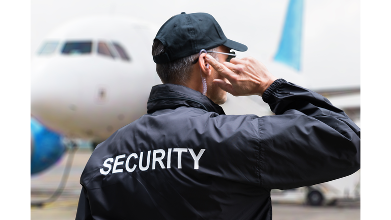 Security Guard Listening To Earpiece Against Building