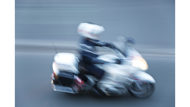 Police motorcyclist riding down street