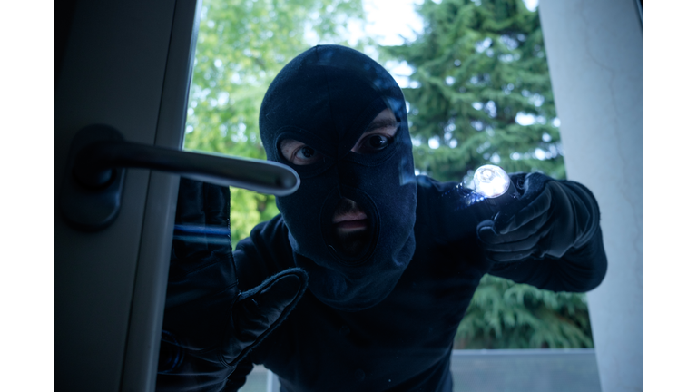 Burglar wearing a balaclava looking through the house window