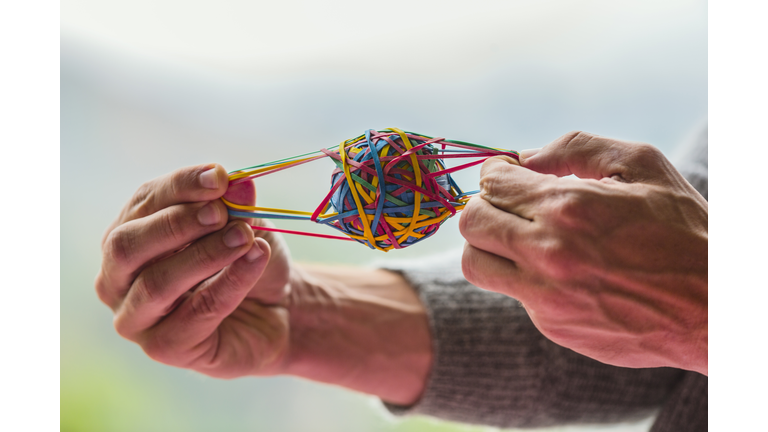 Close up of Caucasian man pulling rubber band ball