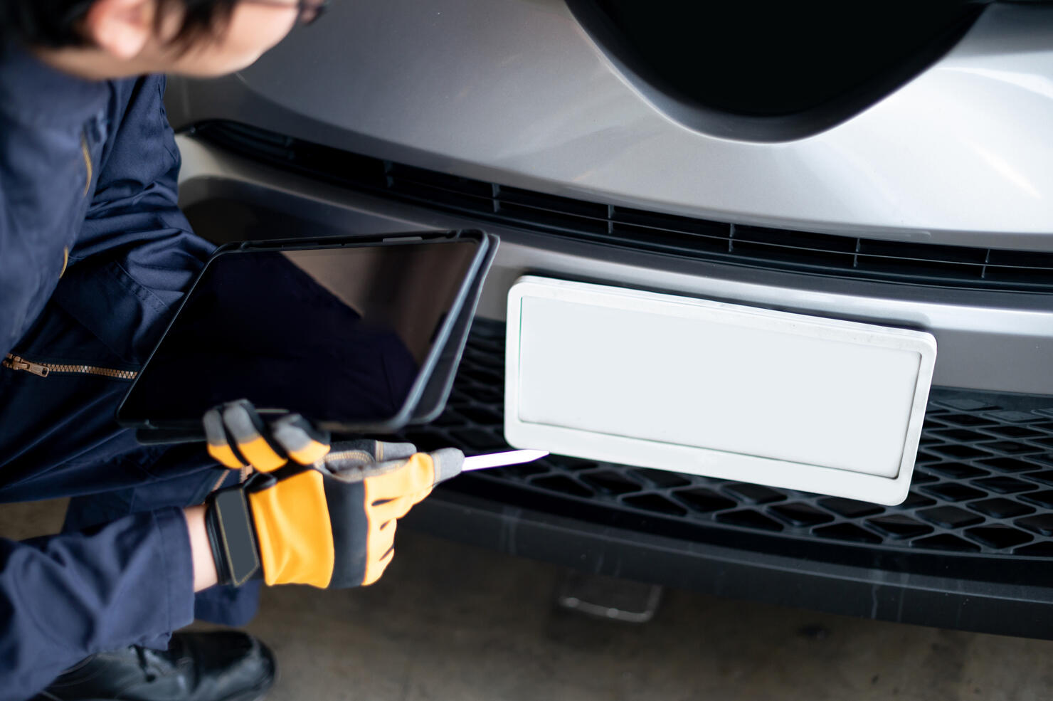 Asian auto mechanic checking the car using tablet