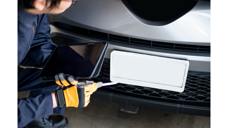 Asian auto mechanic checking the car using tablet