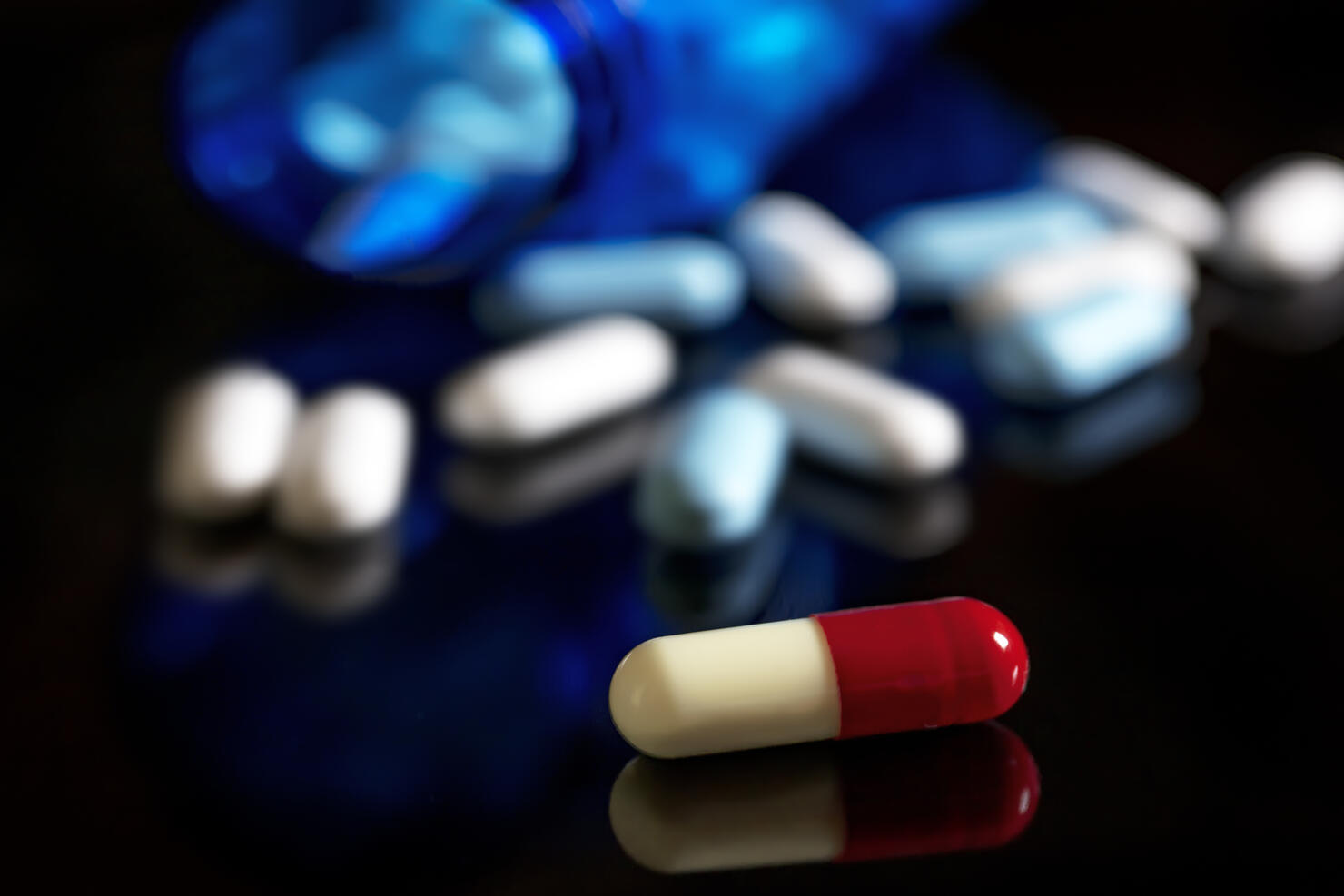 Spilled capsules and pills On black background. Medical concept