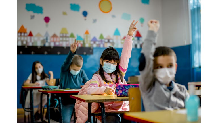 Elementary schoolchildren wearing a protective face masks  in the classroom. Education during epidemic.