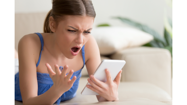 Shocked young woman using digital tablet at home