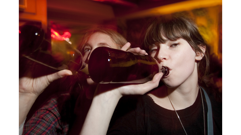 Two Attractive Young Women Drinking Beers at a Bar