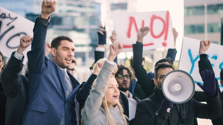 Multicultural Diverse Office Managers and Business People Picketing Outside on a Street. Men and Women Screaming for Justice, Holding a Megaphone, Picket Signs and Posters. Economic Crisis Strike.