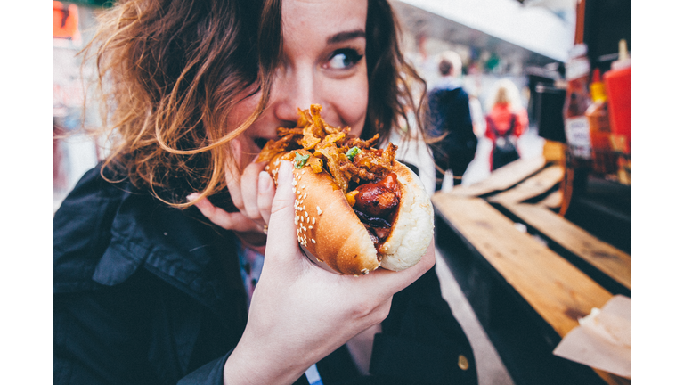 Close-Up Of Young Woman Eating Hot Dog On Street