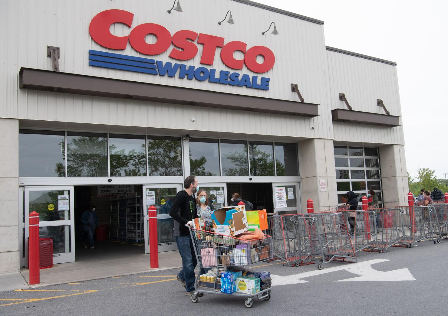 Shoppers walk out with full carts from a Costco store 