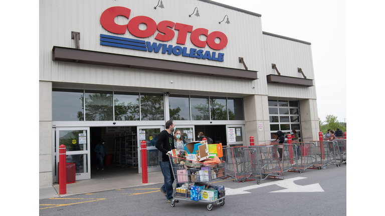 Shoppers walk out with full carts from a Costco store 