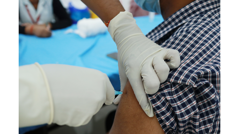 gloved hand giving injection in a shoulder.corona virus vaccination concept.