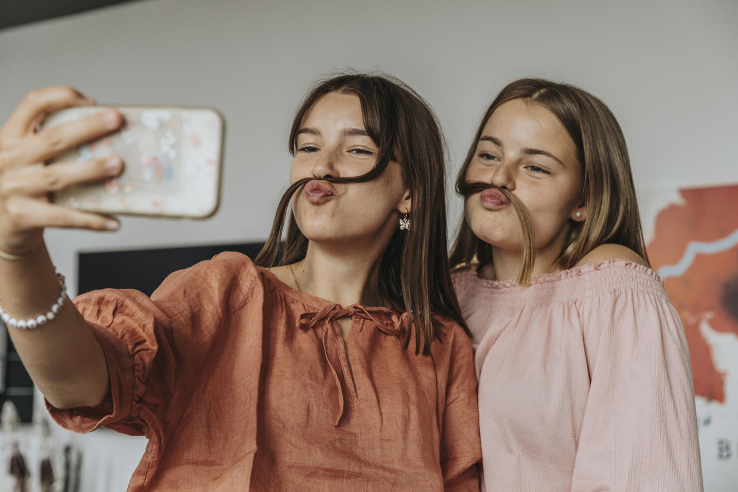 Friends making fake mustache with hair while taking selfie at home