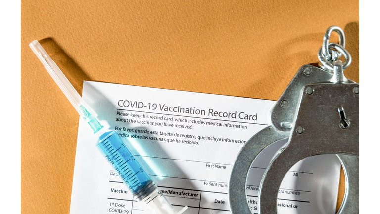 Covid-19 vaccination record, syringe and handcuff. Top view