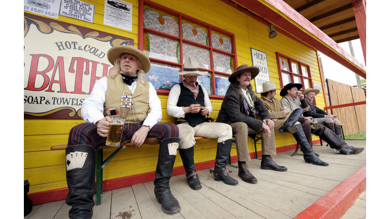 Men dressed up as cowboys sit outside th