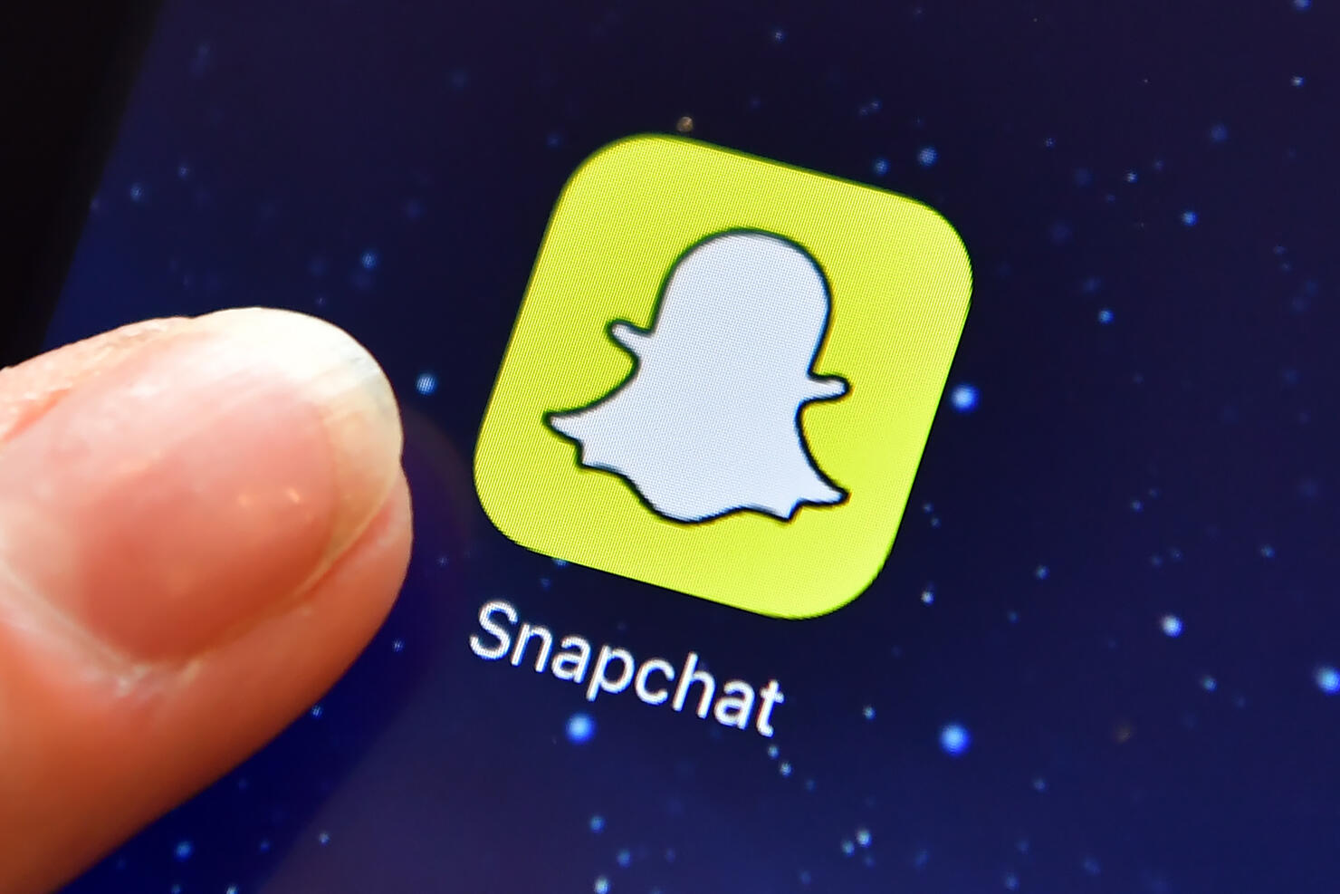 A finger next to the Snapchat app logo 