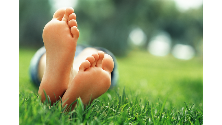 Young woman lying in grass with crossed feet