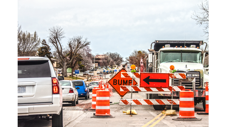 Trucks and road equipment on road with one lane blocked to horizon in urban area an cars navigation the construction