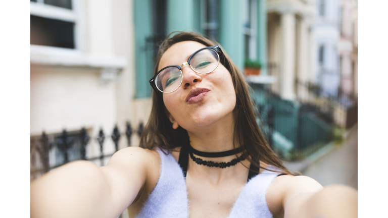 Happy teenage girl in the city taking a selfie