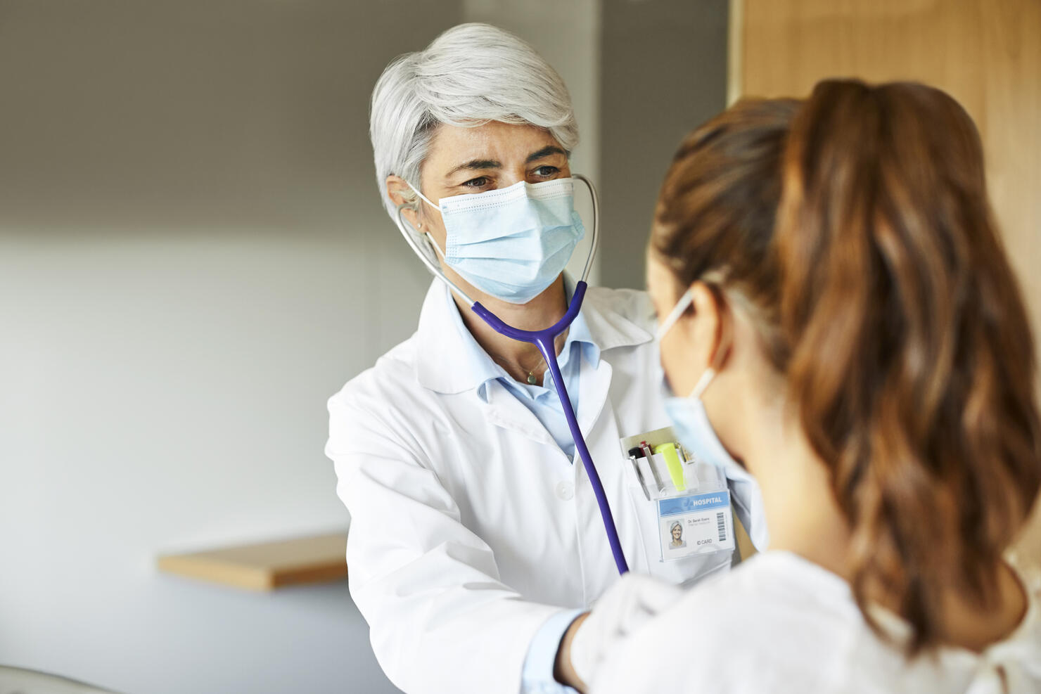 Doctor examining female through stethoscope in ICU