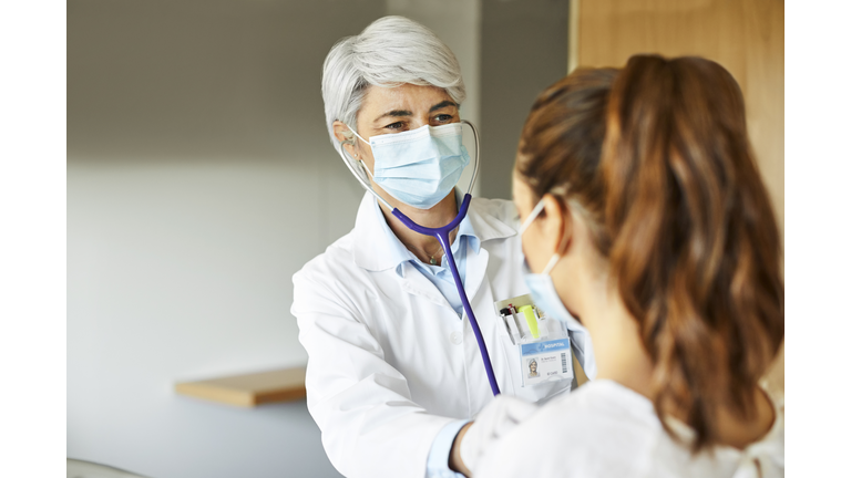 Doctor examining female through stethoscope in ICU