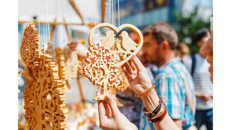 A woman tourist at a souvenir fair choosing handmade decorative woodcarving gifts