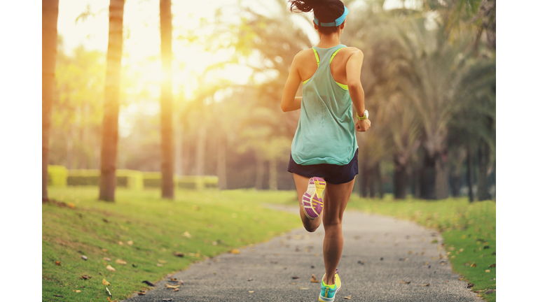 healthy lifestyle young sporty asian woman running at tropical park