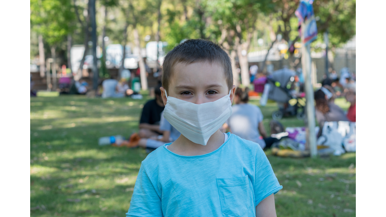 Little child boy looking at the camera using a protective mask