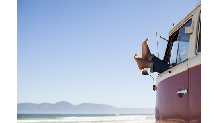 Feet sticking out of camper van window at beach