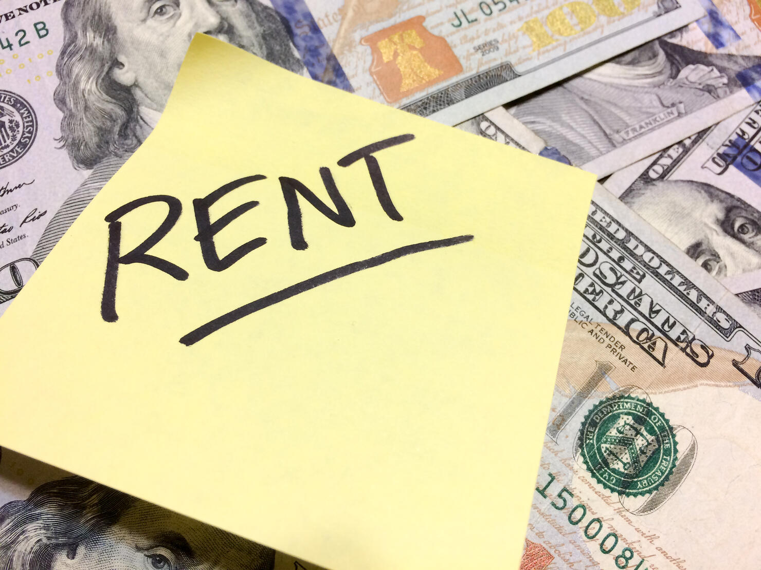 American cash money and yellow post it note with text Rent