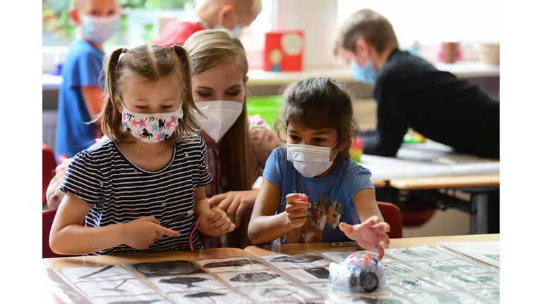 Two young students and teacher wear masks