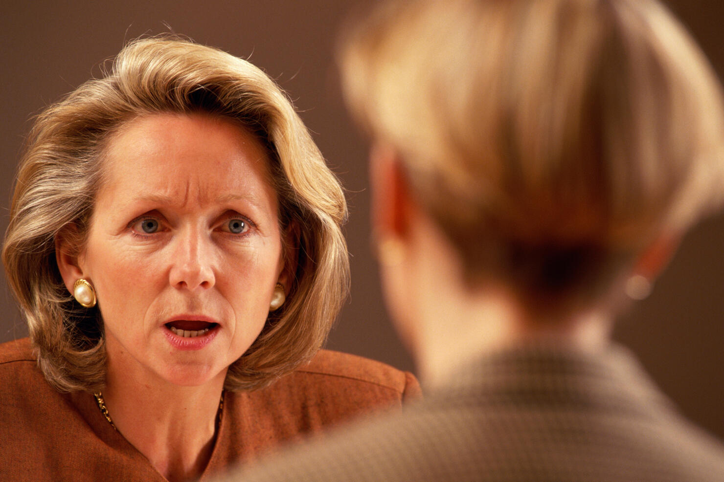 WOMAN TALKING W/STERN FACE TO CO-WORKER