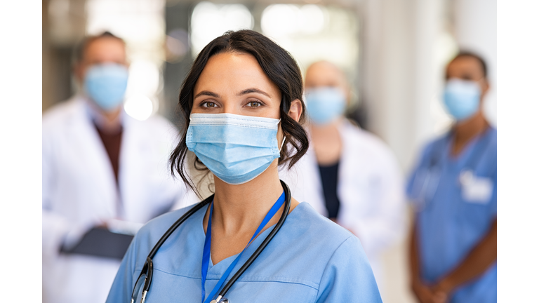 Happy nurse with face mask smiling at hospital