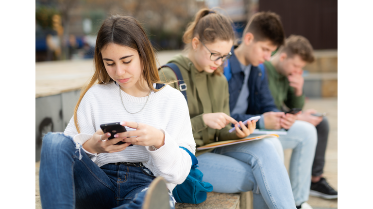 Addicted teen girl using smartphone outdoors