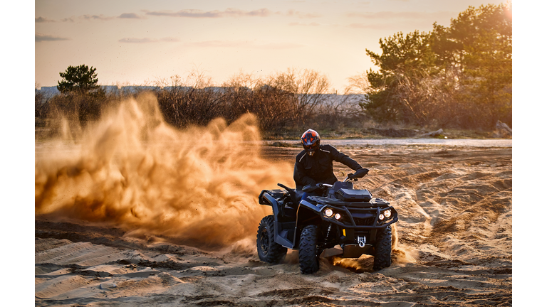 Racing powerful quad bike on the difficult sand in the summer.