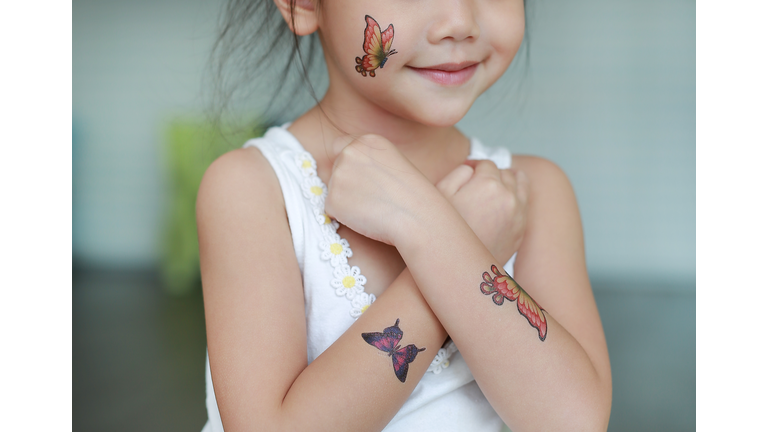 Midsection Of Girl With Artificial Butterfly Tattoos On Body Parts At Home