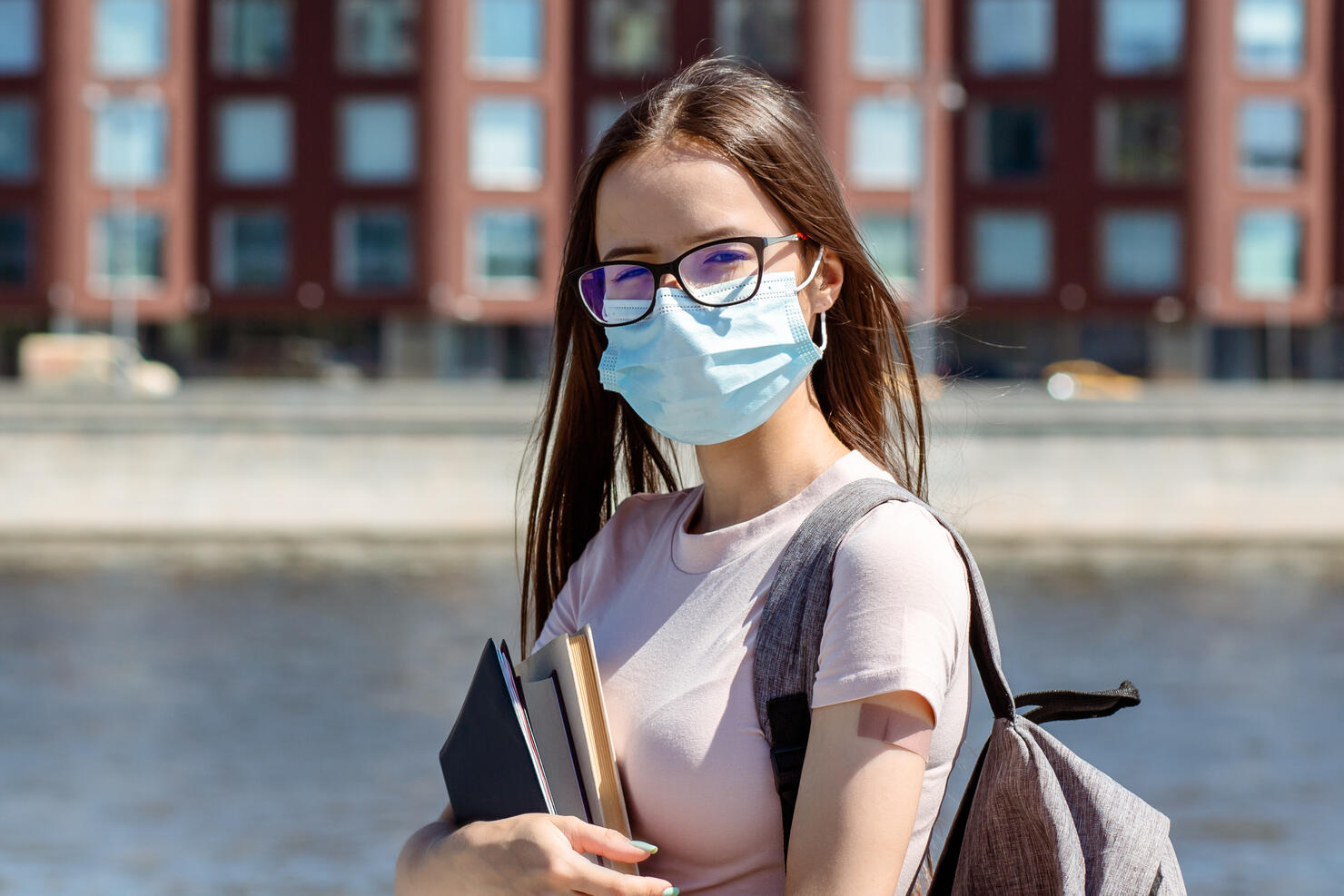 student teenage girl in medical protective mask with plaster on hand back to school after summer vacation, teenagers get the vaccine against covid-19