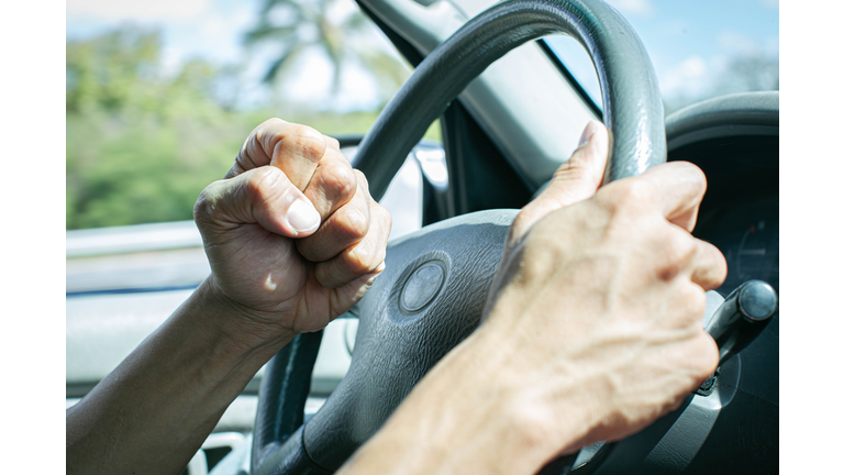 Angry driver honking and beeping the horn. Road rage.